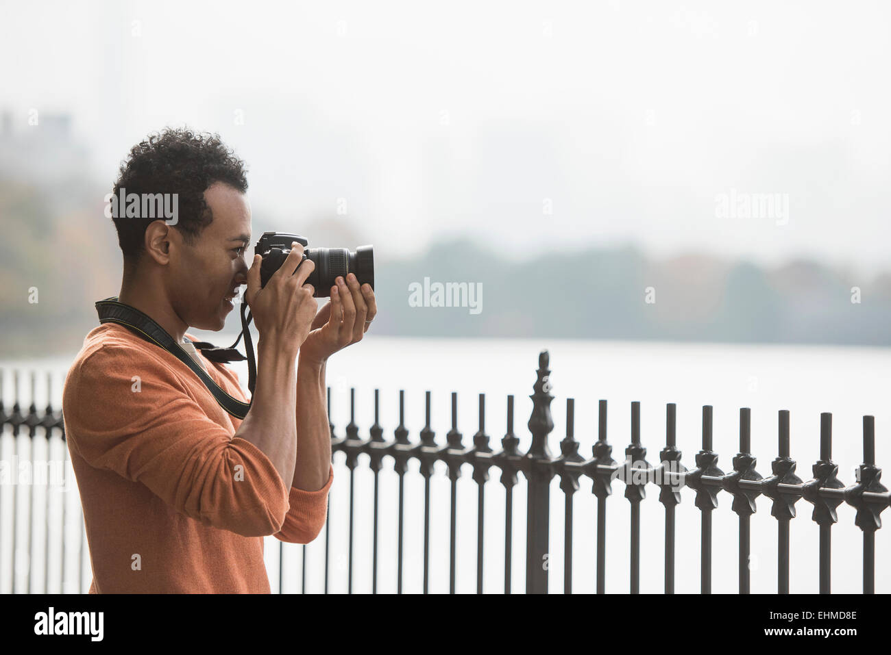 Mixed race man taking photograph on waterfront Stock Photo