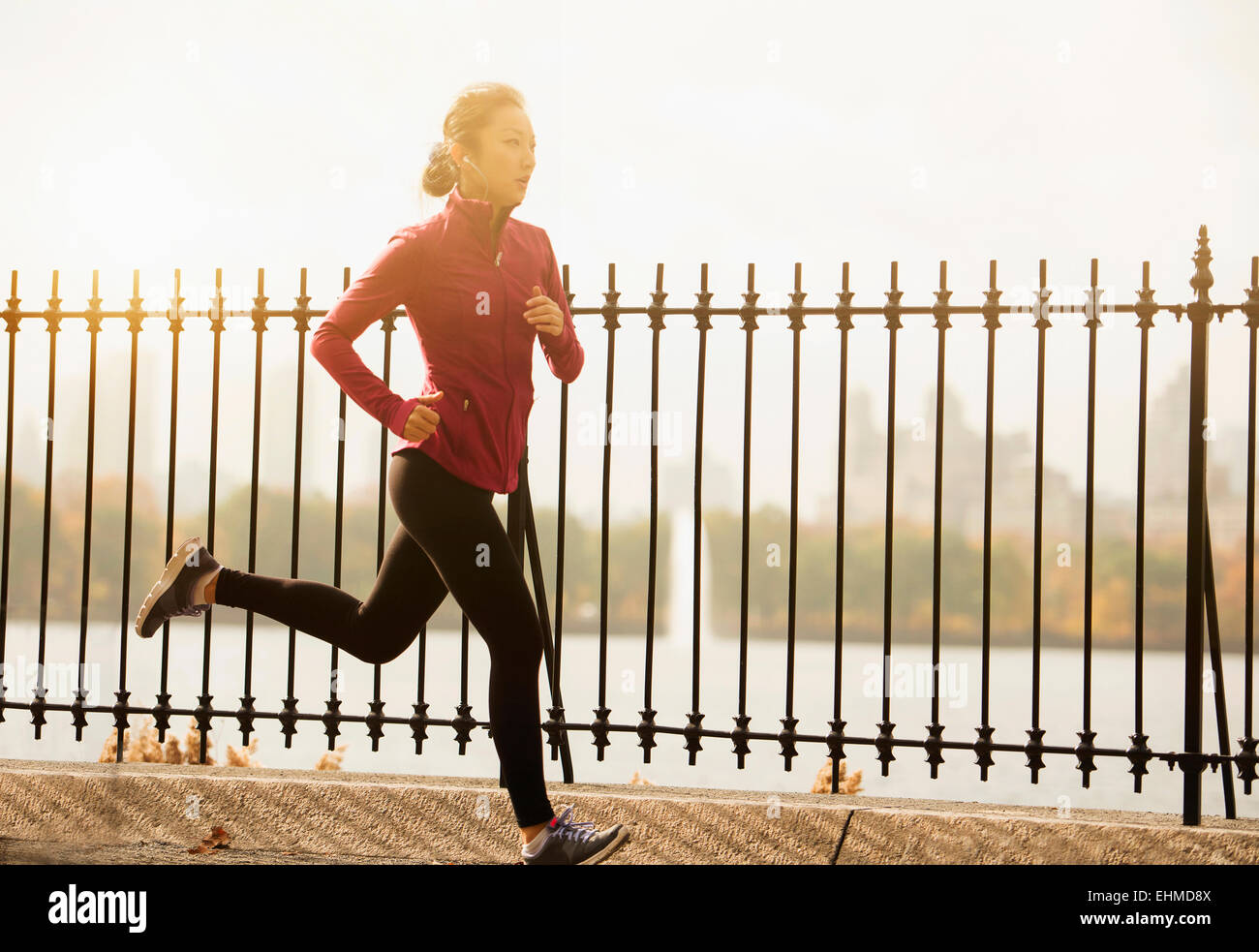 Asian woman running on waterfront path Stock Photo