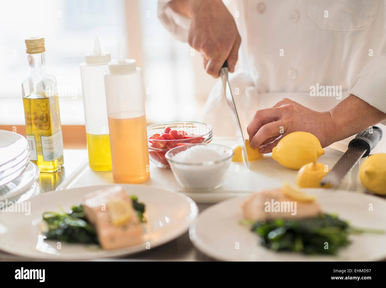 Korean chef slicing lemons in kitchen Stock Photo