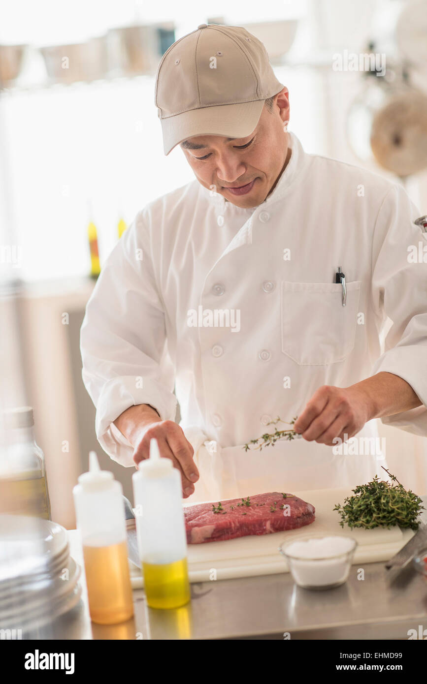 Korean chef seasoning meat in kitchen Stock Photo