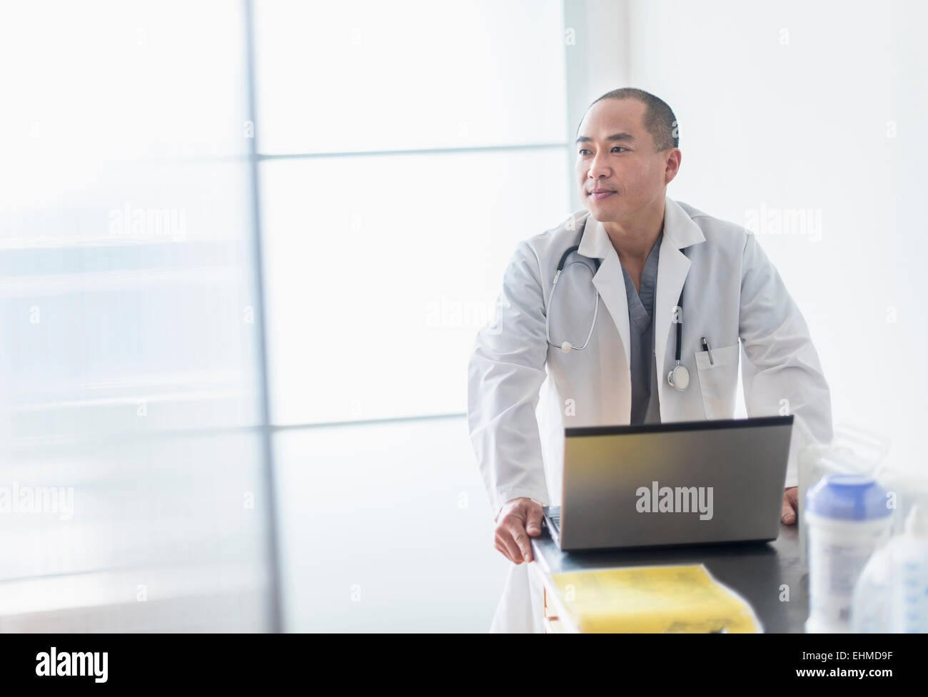 Korean doctor standing near laptop in office Stock Photo