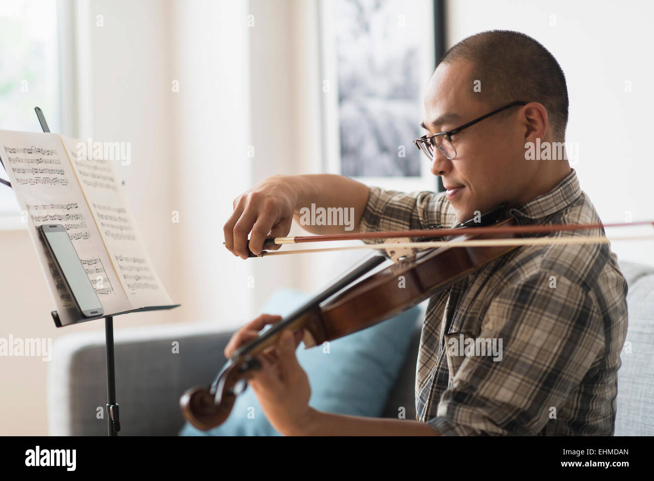 Korean musician playing violin in living room Stock Photo