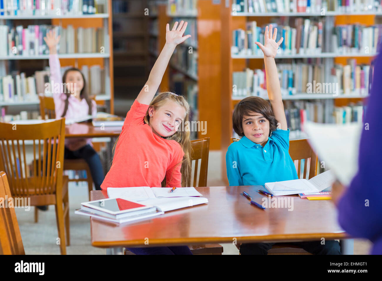 Students raising their hands in library Stock Photo - Alamy