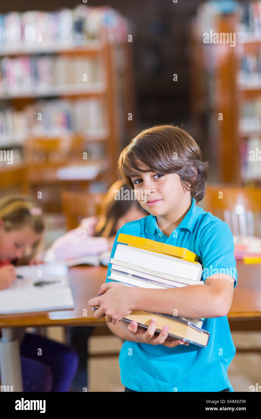 Student carrying stack of books in library Stock Photo