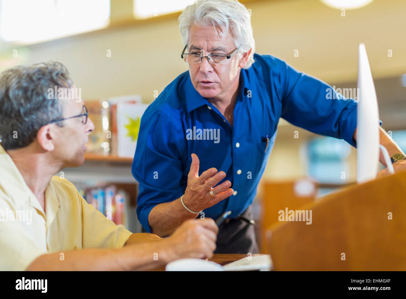 Teacher helping adult student in library Stock Photo