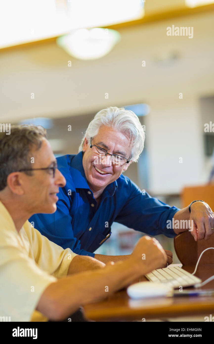 Teacher helping adult student use computer in library Stock Photo - Alamy
