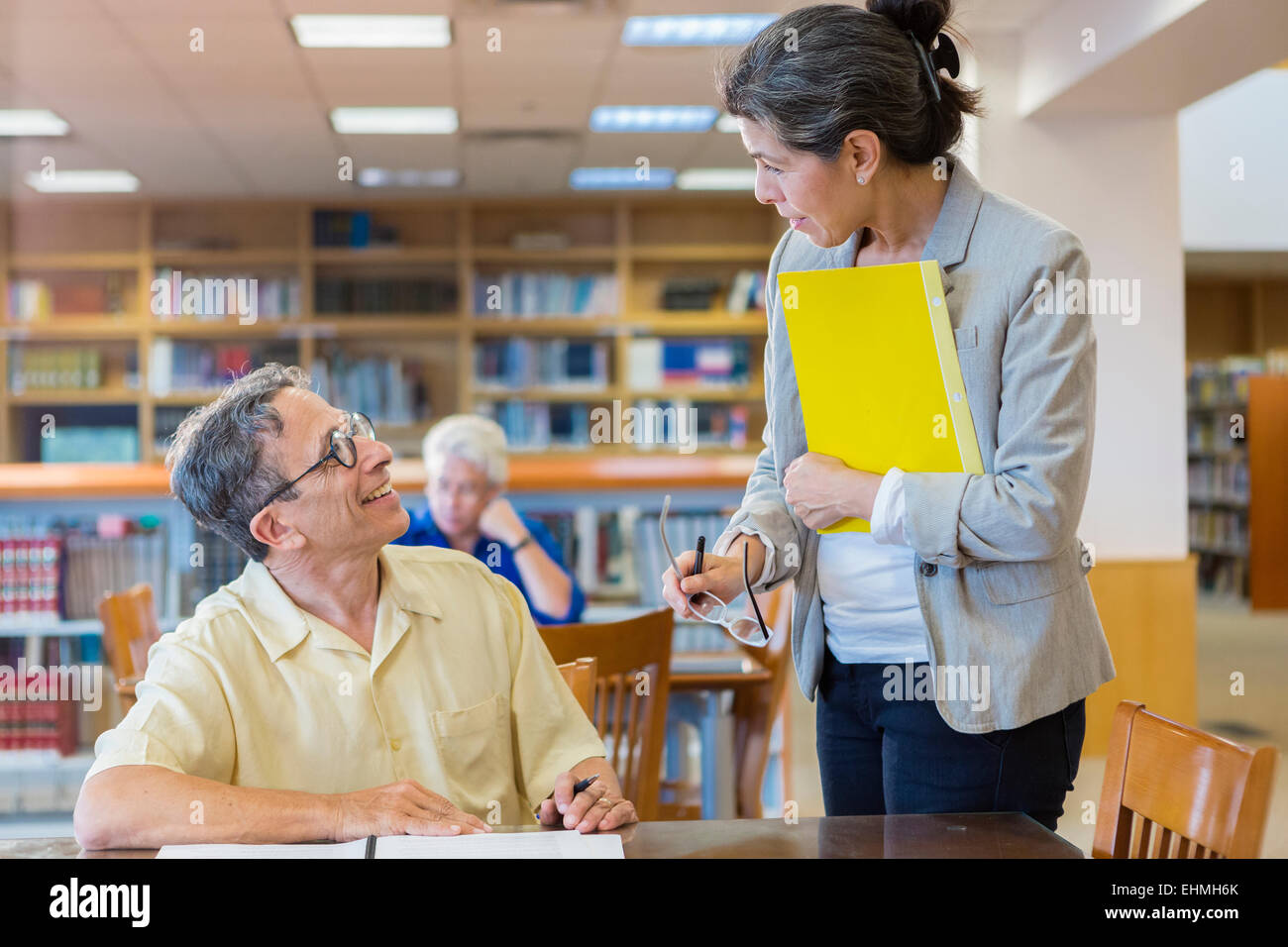 Teacher helping adult student in library Stock Photo