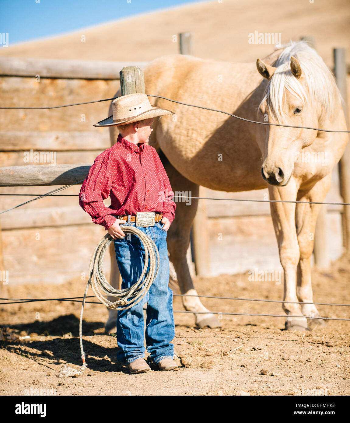 Caucasian boy in cowboy outfit admiring horse on ranch Stock Photo