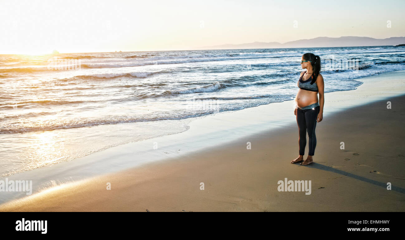 Pregnant Hispanic woman standing on beach Stock Photo