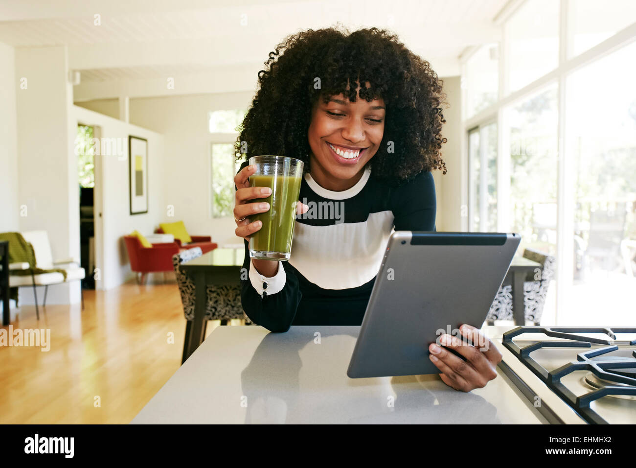 Mixed race woman using digital tablet in domestic kitchen Stock Photo