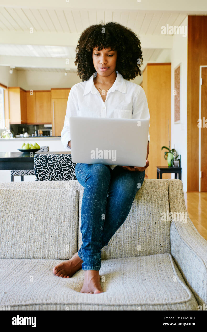 Mixed race woman using laptop on sofa Stock Photo