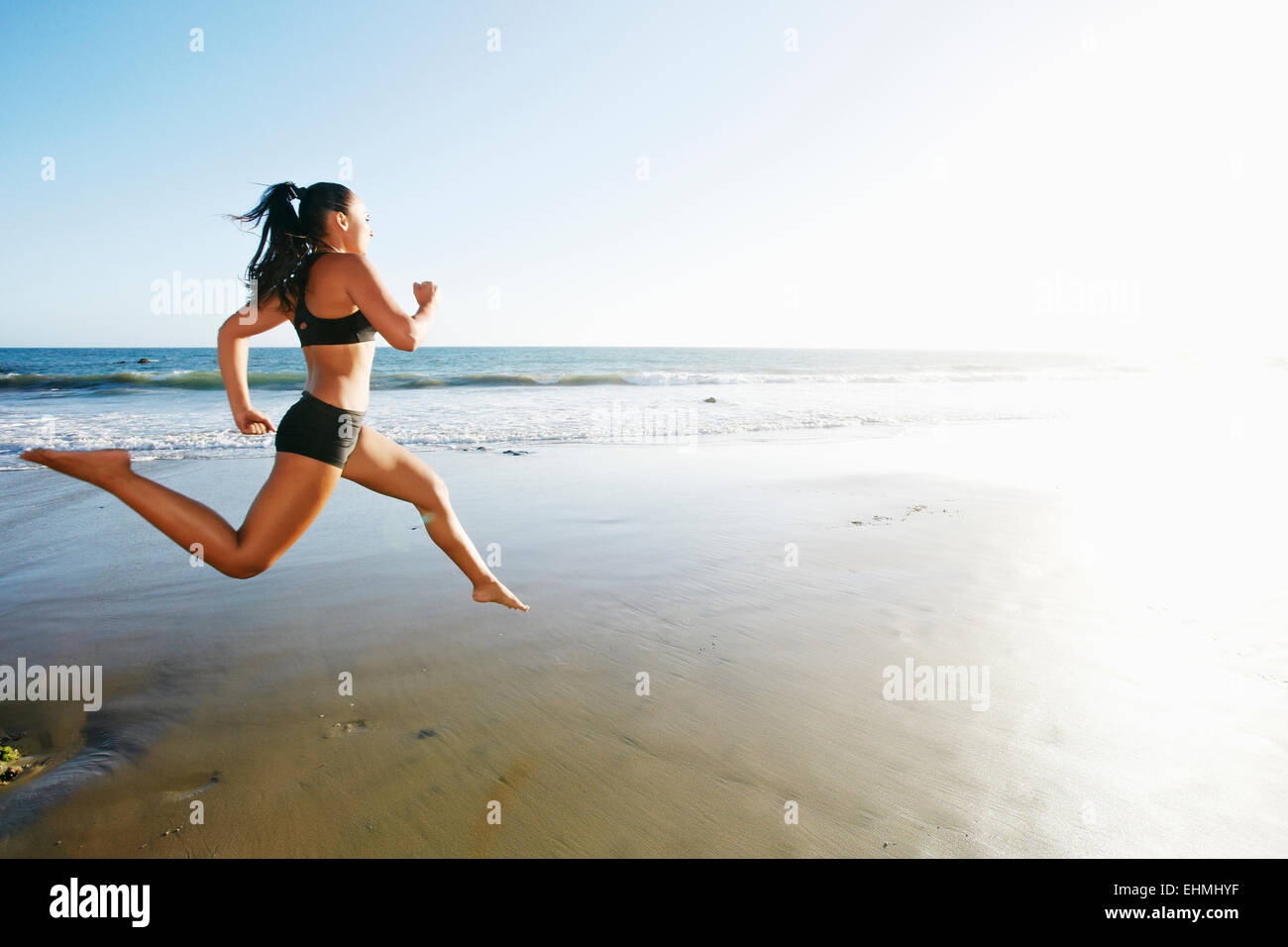 Mixed race woman running on beach Stock Photo