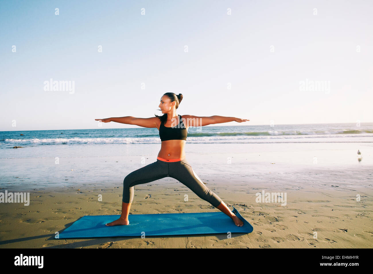 Mixed race woman practicing yoga on beach Stock Photo