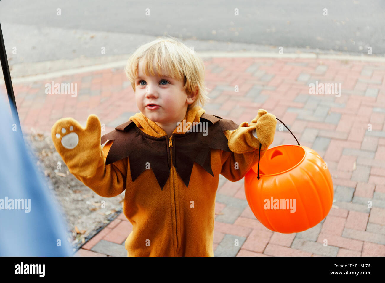 Caucasian boy in lion costume trick or treating on Halloween Stock Photo