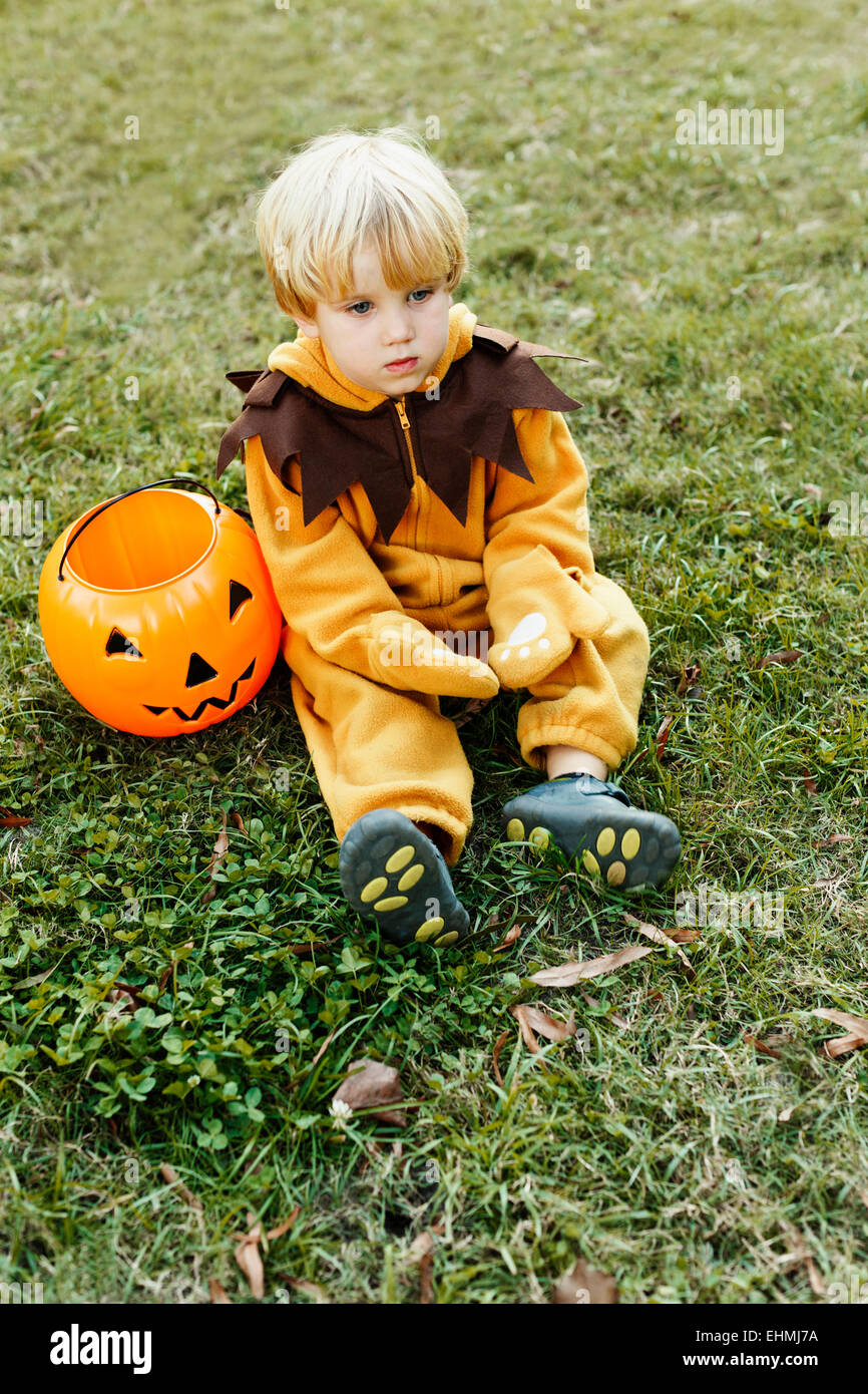 Caucasian boy in lion costume sitting on grass on Halloween Stock Photo