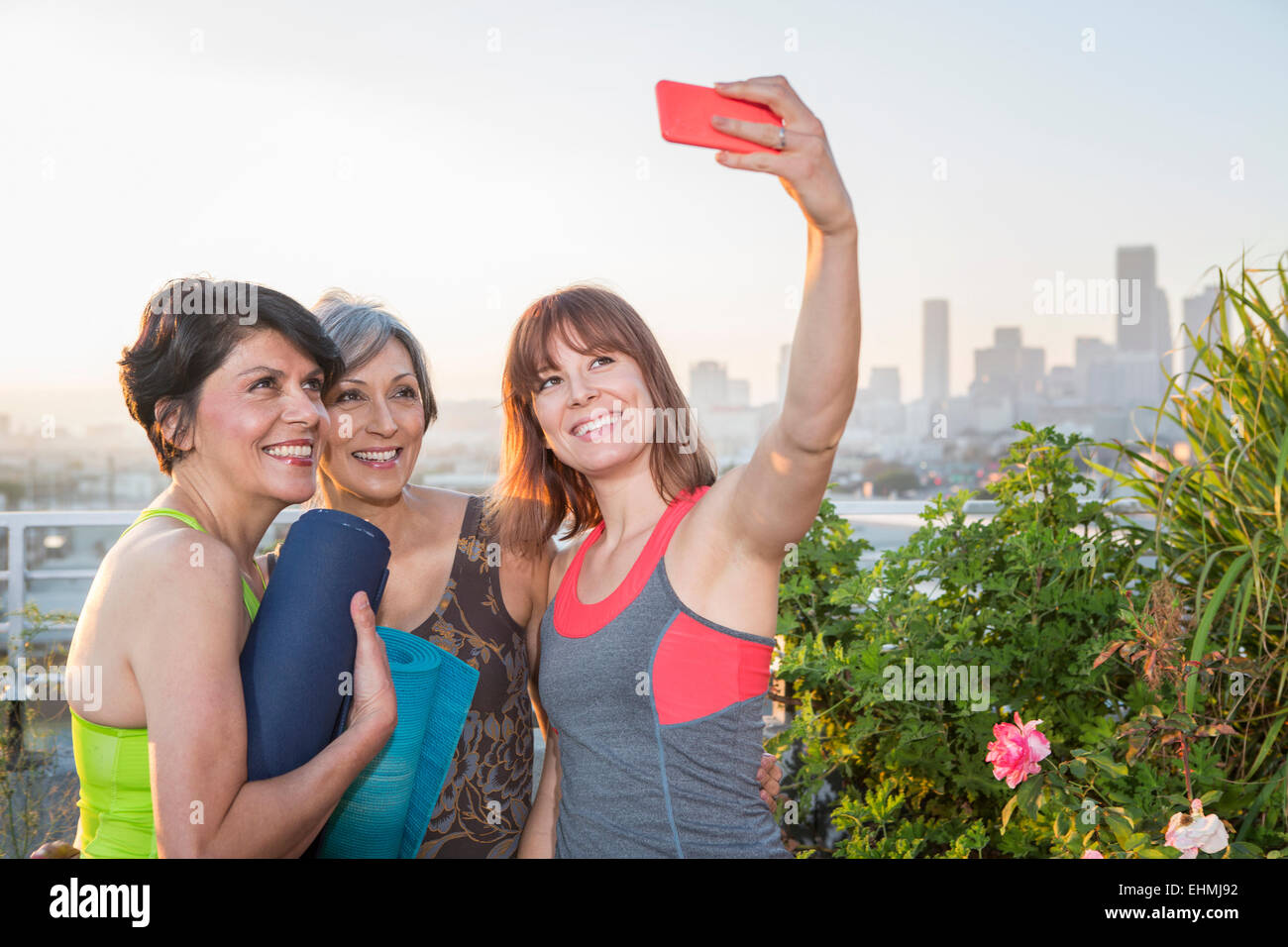 Women taking cell phone selfie on urban rooftop Stock Photo