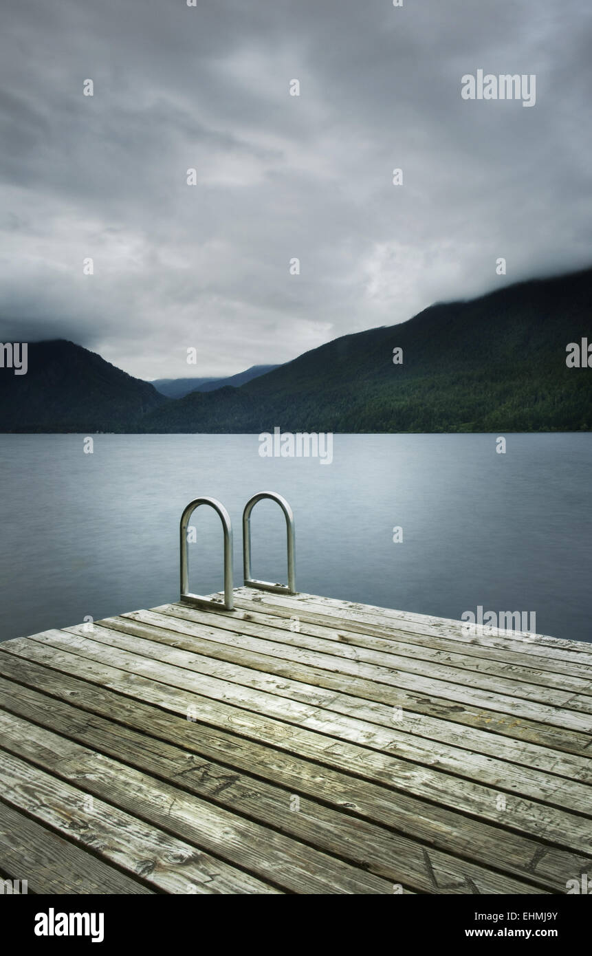 Ladder on wooden pier near still remote lake Stock Photo