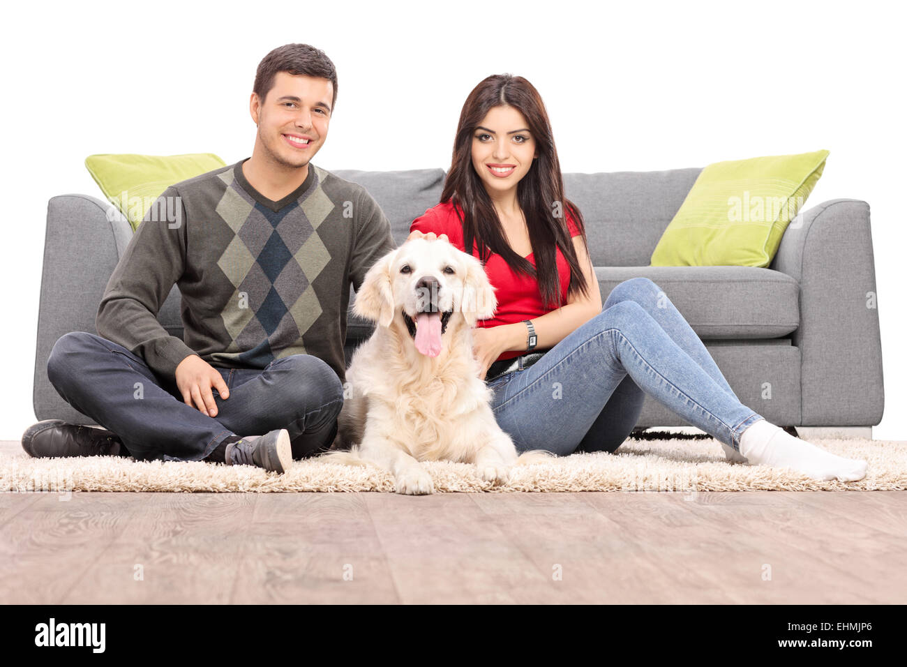 Young couple sitting on the floor with a dog isolated on white background Stock Photo