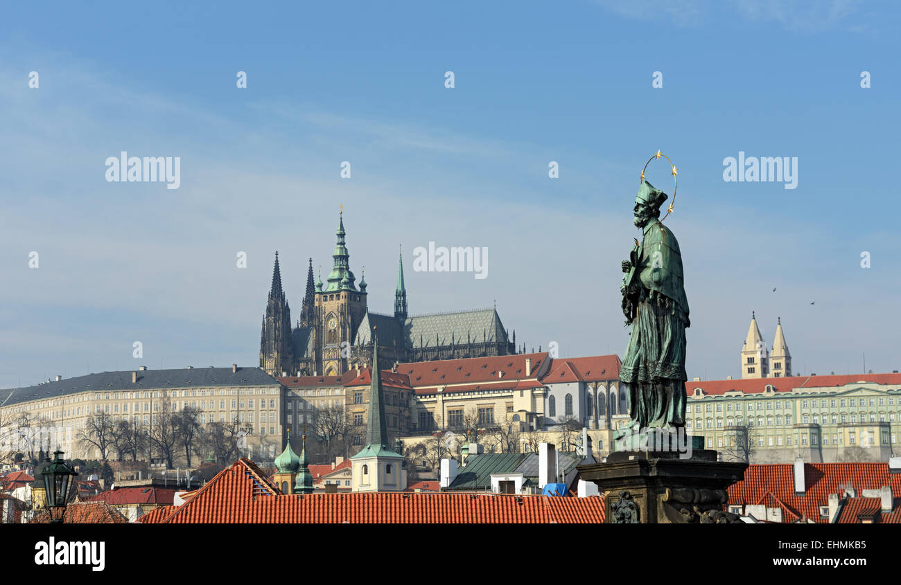 St. John of Nepomuk, one of famous statues of Charles Bridge on background of Prague Castle  with Saint Vitus Cathedral in Pragu Stock Photo