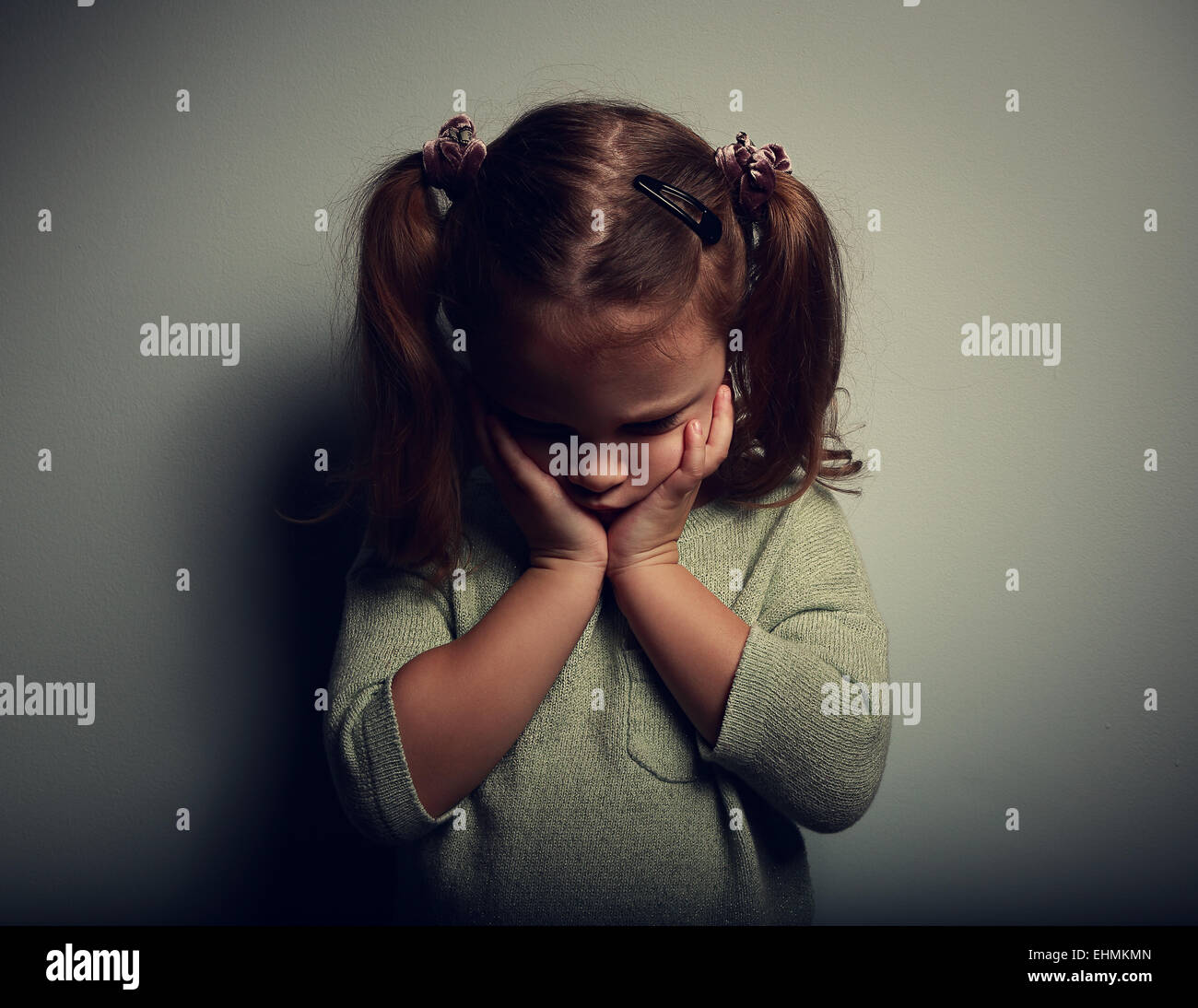 Sad crying alone kid girl on dark background. Closeup portrait Stock Photo