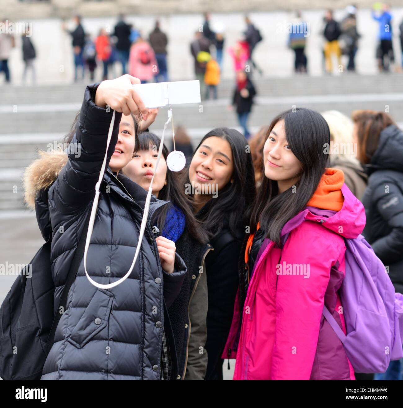 Group of Japanese tourists, girls posing for a selfie in Trafalgar Square, London Stock Photo