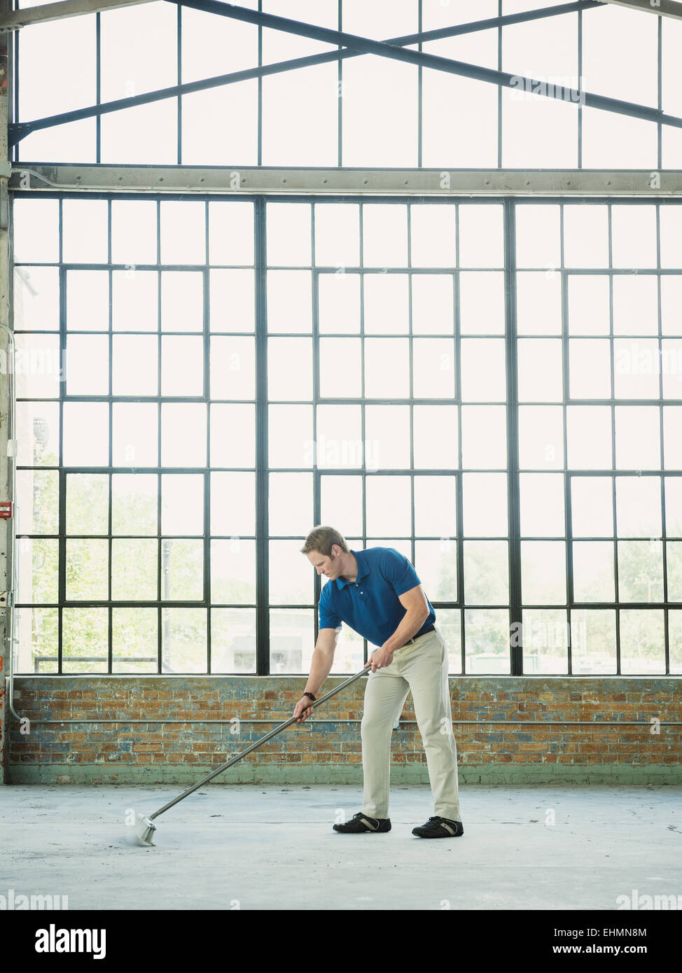 Caucasian businessman sweeping warehouse floor Stock Photo