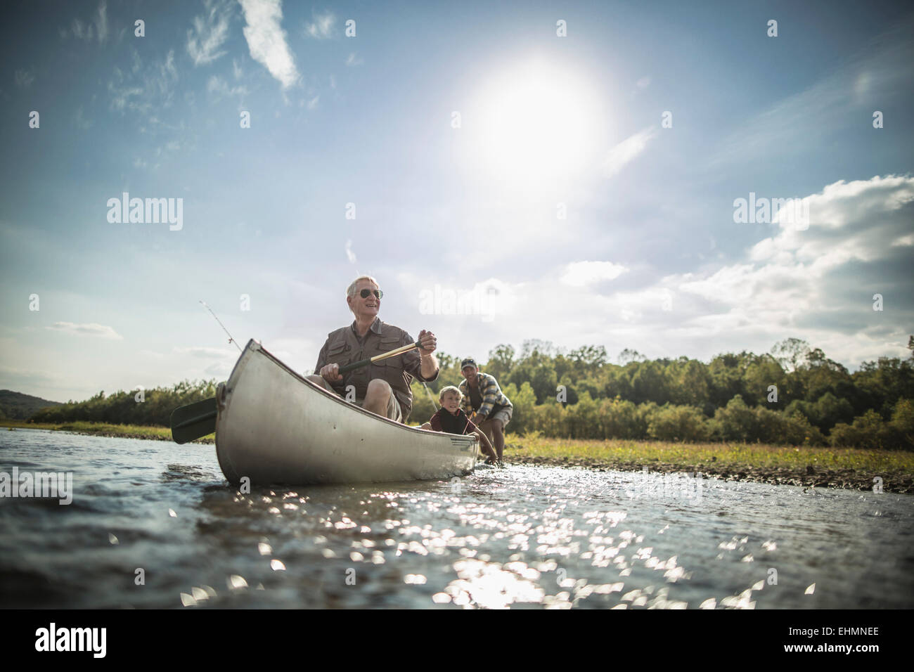 Three generations of Caucasian men paddling canoe in river Stock Photo