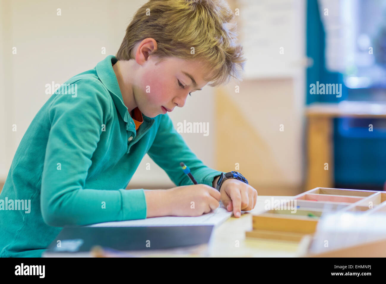 Caucasian boy writing in classroom Stock Photo
