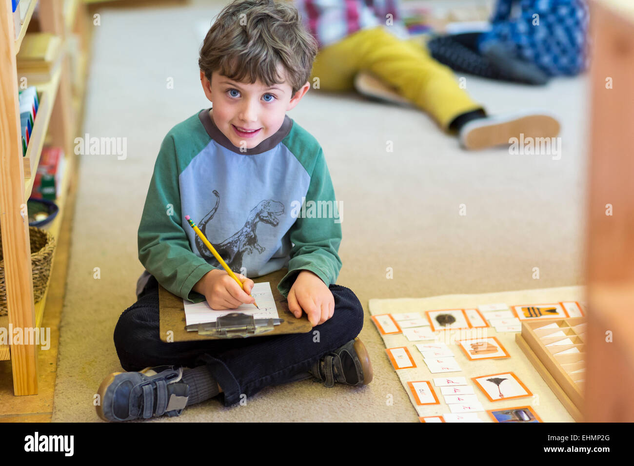 Smiling boy writing in classroom Stock Photo