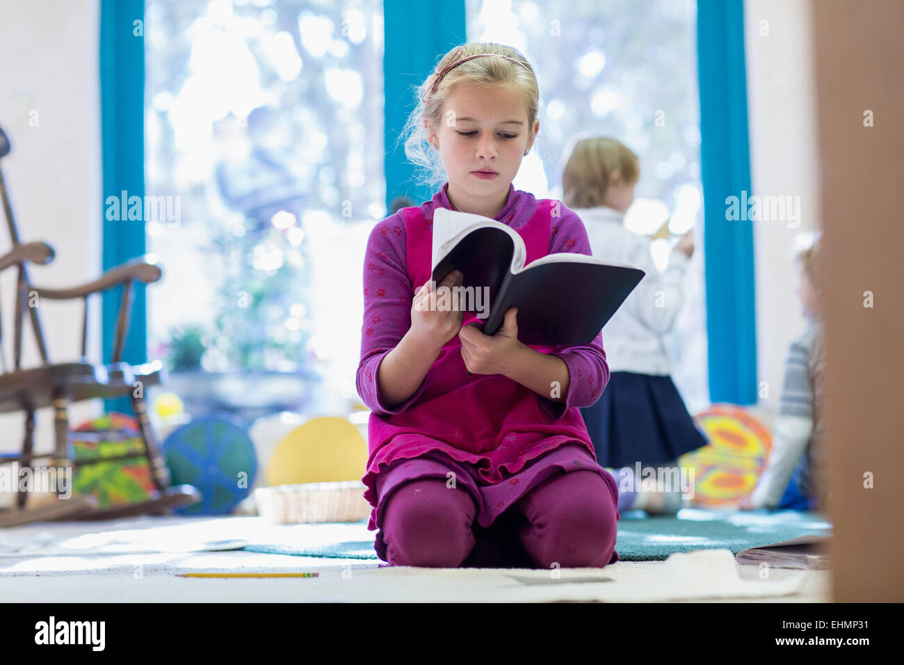 Caucasian girl reading book on floor Stock Photo