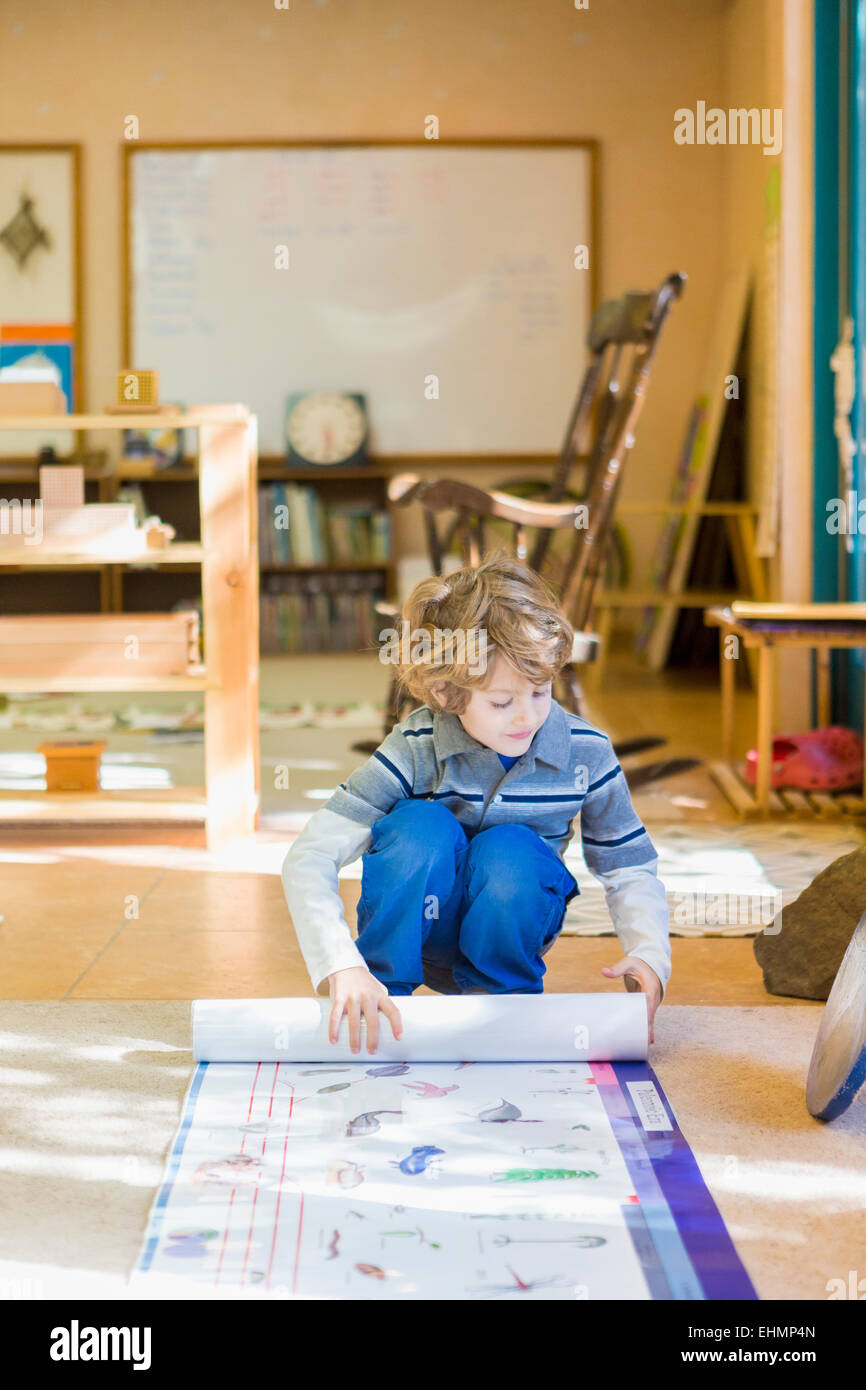 Boy rolling up poster in classroom Stock Photo Alamy