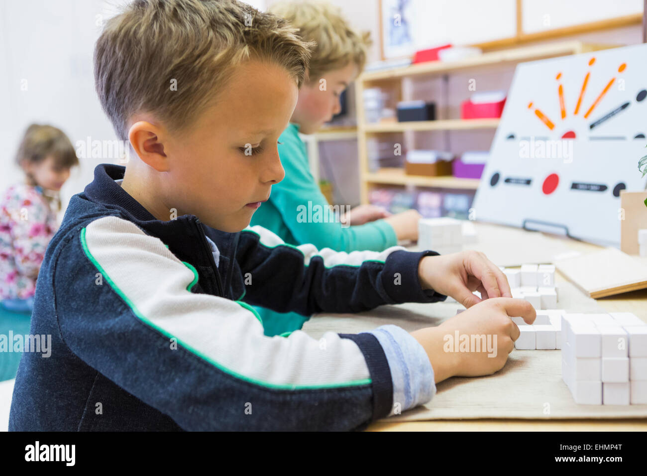 Close up of boy solving puzzle in classroom Stock Photo