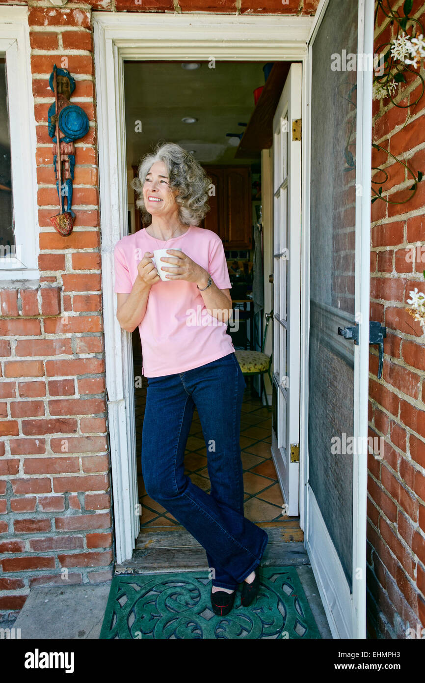 Caucasian woman drinking cup of coffee in doorway Stock Photo