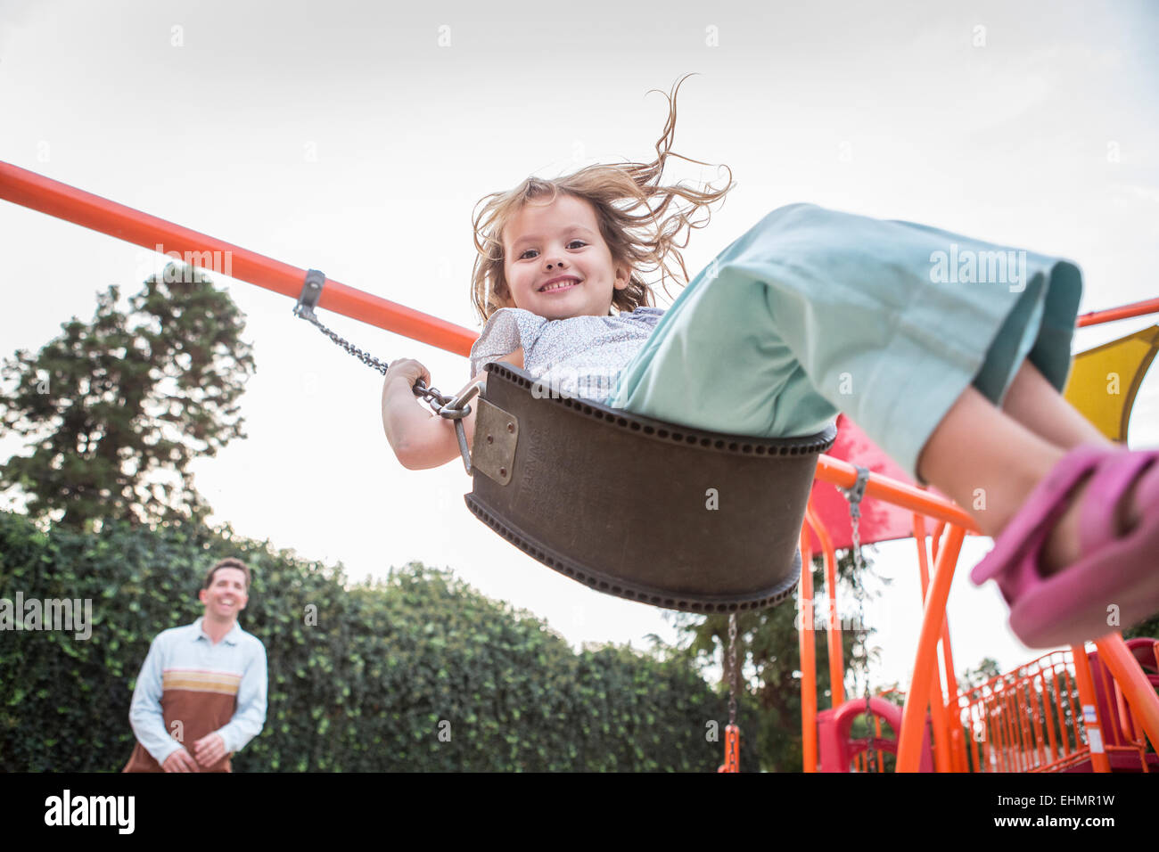 Caucasian father pushing daughter on swing Stock Photo