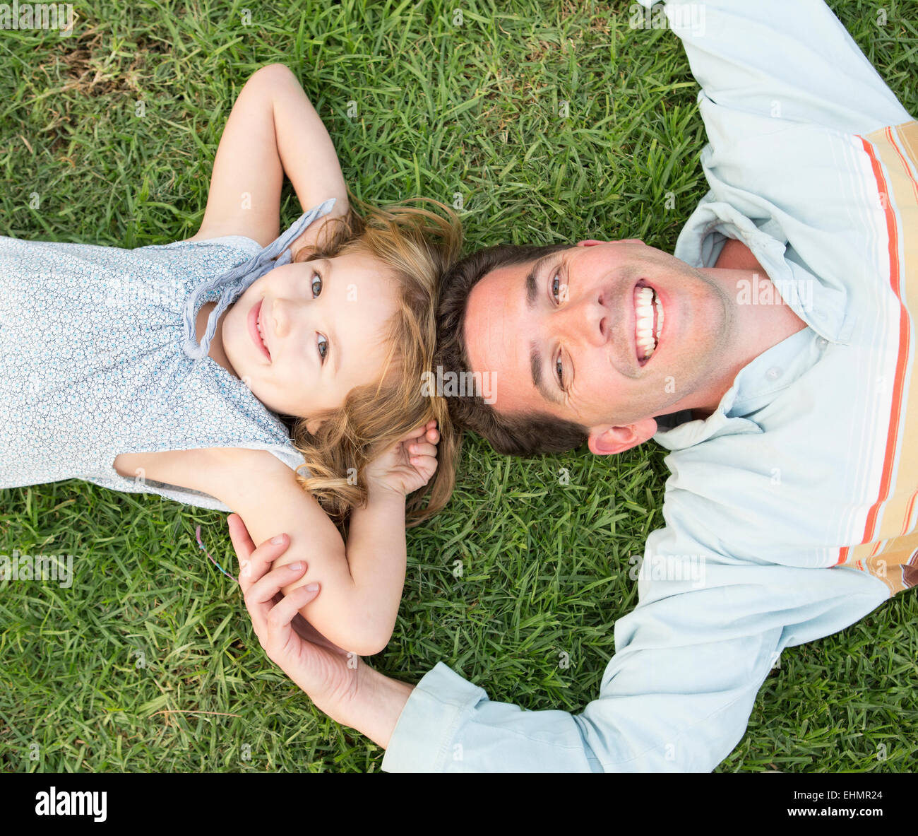Caucasian father and daughter laying on grass Stock Photo