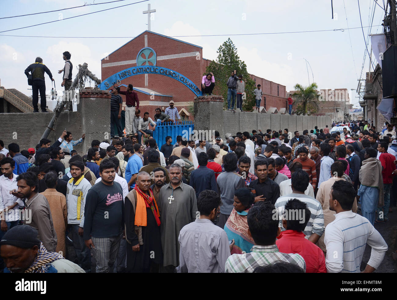 Lahore, Pakistan. 15th March, 2015. People gather around the burning bodies of what the mob called suspects in aiding the suicide bombers nearby the scene of an attack on a church in Lahore, Pakistan, 15 March 2015. Two Taliban suicide bombers blew themselves up outside two churches in the impoverished Yohana Abad sector of eastern Lahore during Sunday mass, killing at least 11 worshippers and wounding several others, officials said, in the latest attack against religious minorities. Credit:  PACIFIC PRESS/Alamy Live News Stock Photo