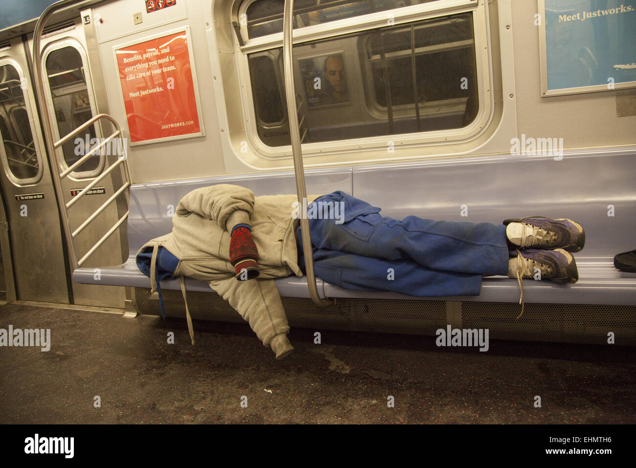 Homeless man sleeps in the early morning on a New York City subway train. Stock Photo
