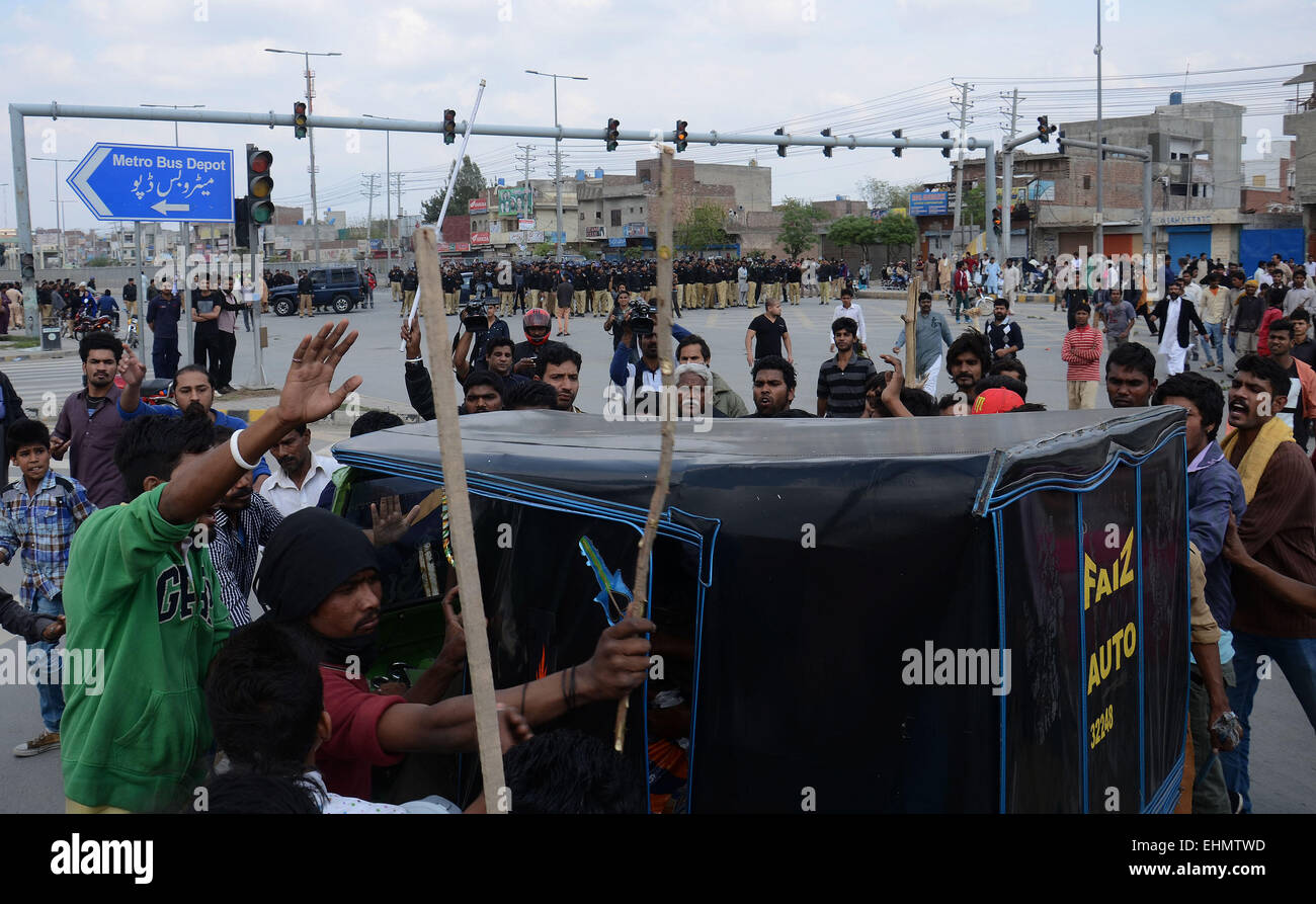 Lahore, Pakistan. 15th March, 2015. People around bringing small sticks and halt other vehicles to pass the way. There are bunch of Pakistani gather around the burning bodies of what the mob called suspects in aiding the suicide bombers nearby the scene of an attack on a church, killing at least 11 worshipers and wounding several others, officials said, in the latest attack against religious minorities. An angry mob later lynched two people they accused of aiding the suicide bombers outside the churches, a spokesman for the provincial government said. Credit:  PACIFIC PRESS/Alamy Live News Stock Photo