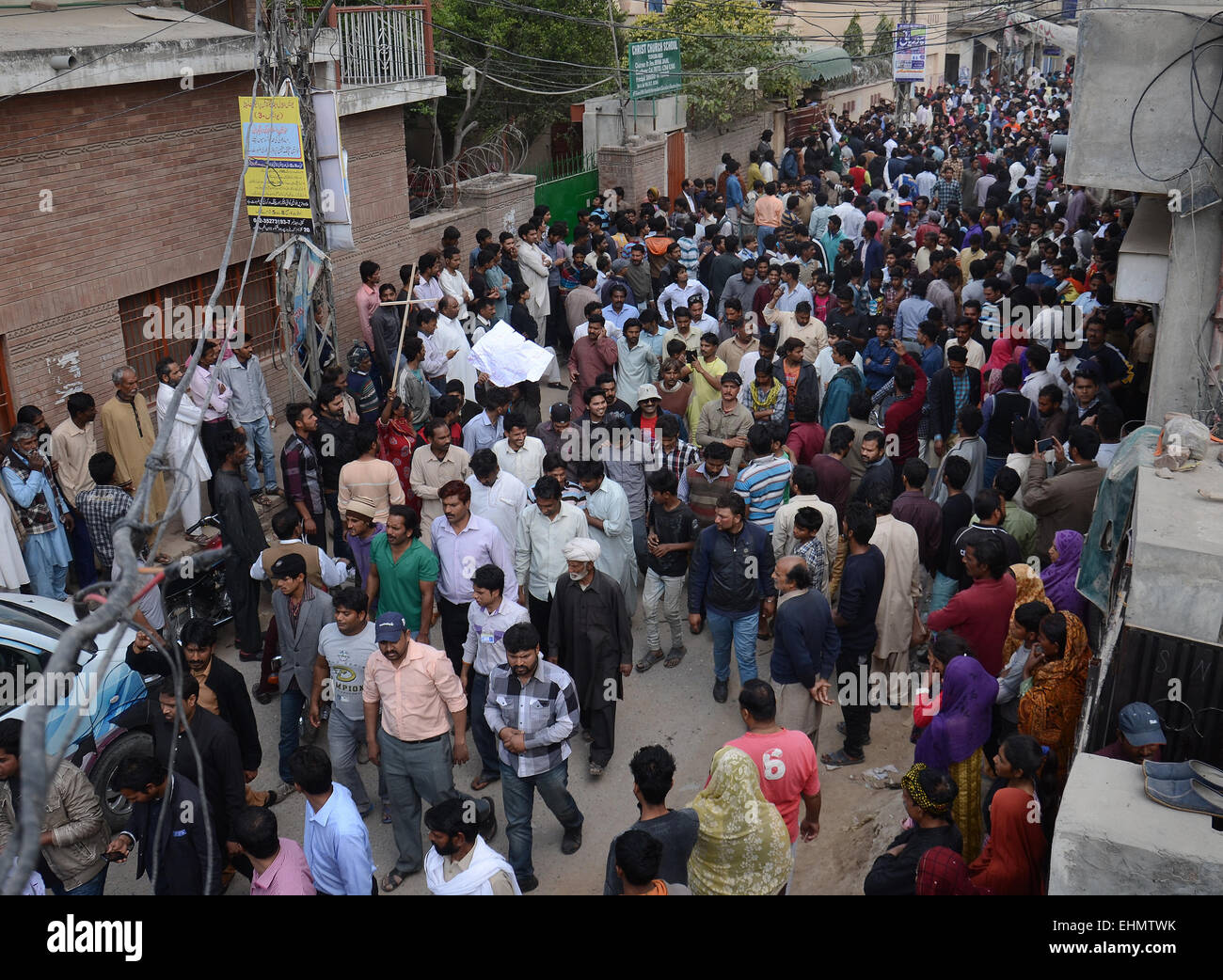 Lahore, Pakistan. 15th March, 2015. People gather around the burning bodies of what the mob called suspects in aiding the suicide bombers nearby the scene of an attack on a church in Lahore, Pakistan, 15 March 2015. Two Taliban suicide bombers blew themselves up outside two churches in the impoverished Yohana Abad sector of eastern Lahore during Sunday mass, killing at least 11 worshipers and wounding several others, officials said, in the latest attack against religious minorities. Credit:  PACIFIC PRESS/Alamy Live News Stock Photo