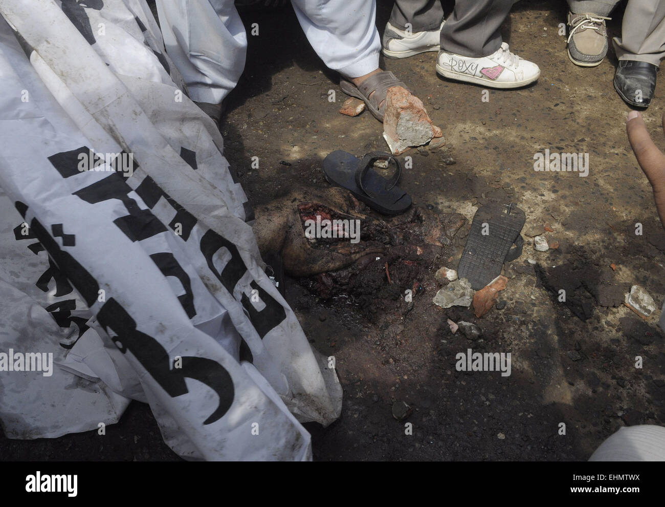 Lahore, Pakistan. 15th March, 2015. People gather around the burning bodies of what the mob called suspects in aiding the suicide bombers nearby the scene of an attack on a church in Lahore, Pakistan, 15 March 2015. Two Taliban suicide bombers blew themselves up outside two churches in the impoverished Yohana Abad sector of eastern Lahore during Sunday mass, killing at least 11 worshipers and wounding several others, officials said, in the latest attack against religious minorities. Credit:  PACIFIC PRESS/Alamy Live News Stock Photo