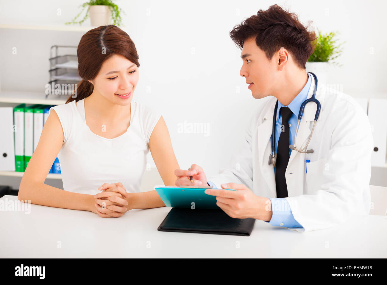 asian doctor talking with female patient in office Stock Photo - Alamy