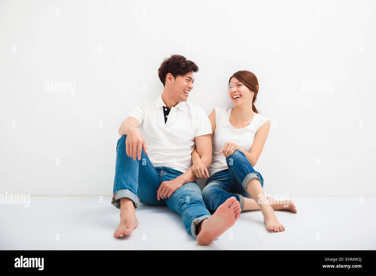 Happy Young asian Couple Sitting On Floor Stock Photo