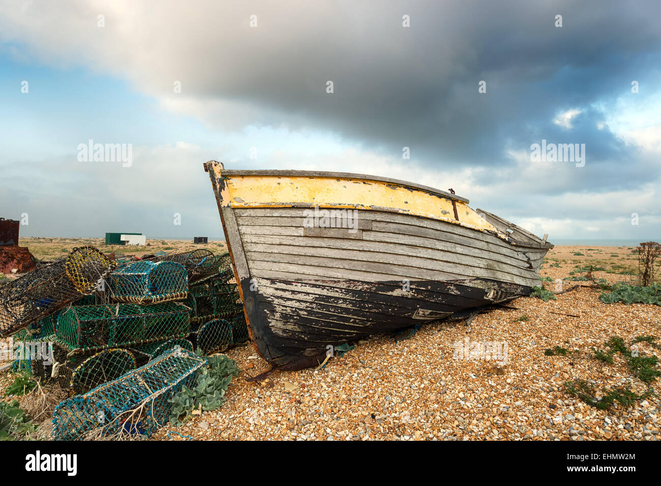 An old wooden fishing boat rests on a shingle beach alongside abandoned ...