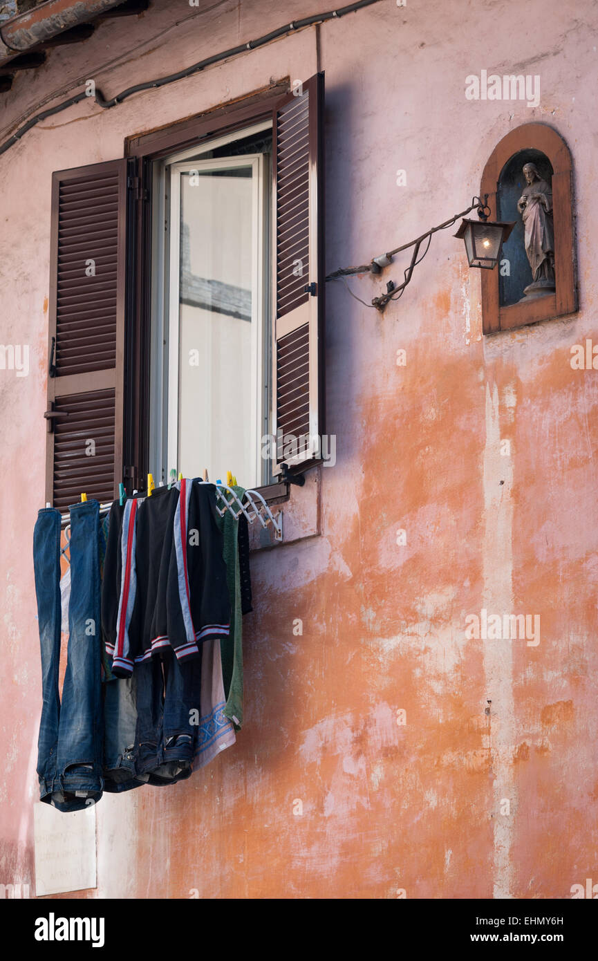 Washing dries next to a statue of a saint, Via della Lungaretta, Trastevere, Rome, Lazio, Italy. Stock Photo