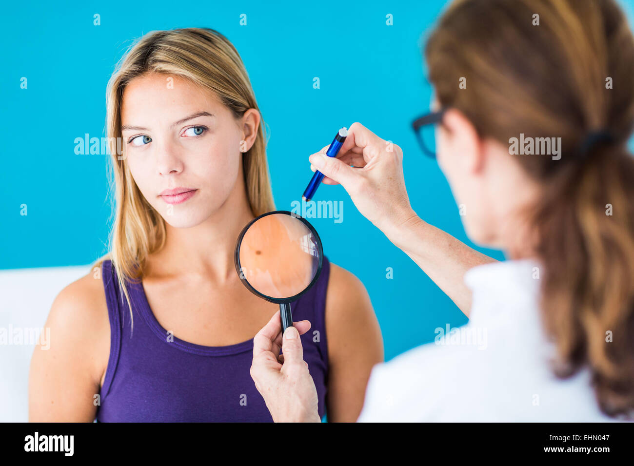 Doctor examining the skin of a woman. Stock Photo