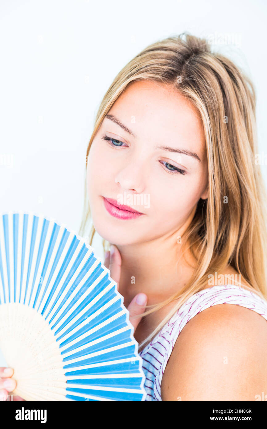 Woman cooling her face with a fan. Stock Photo