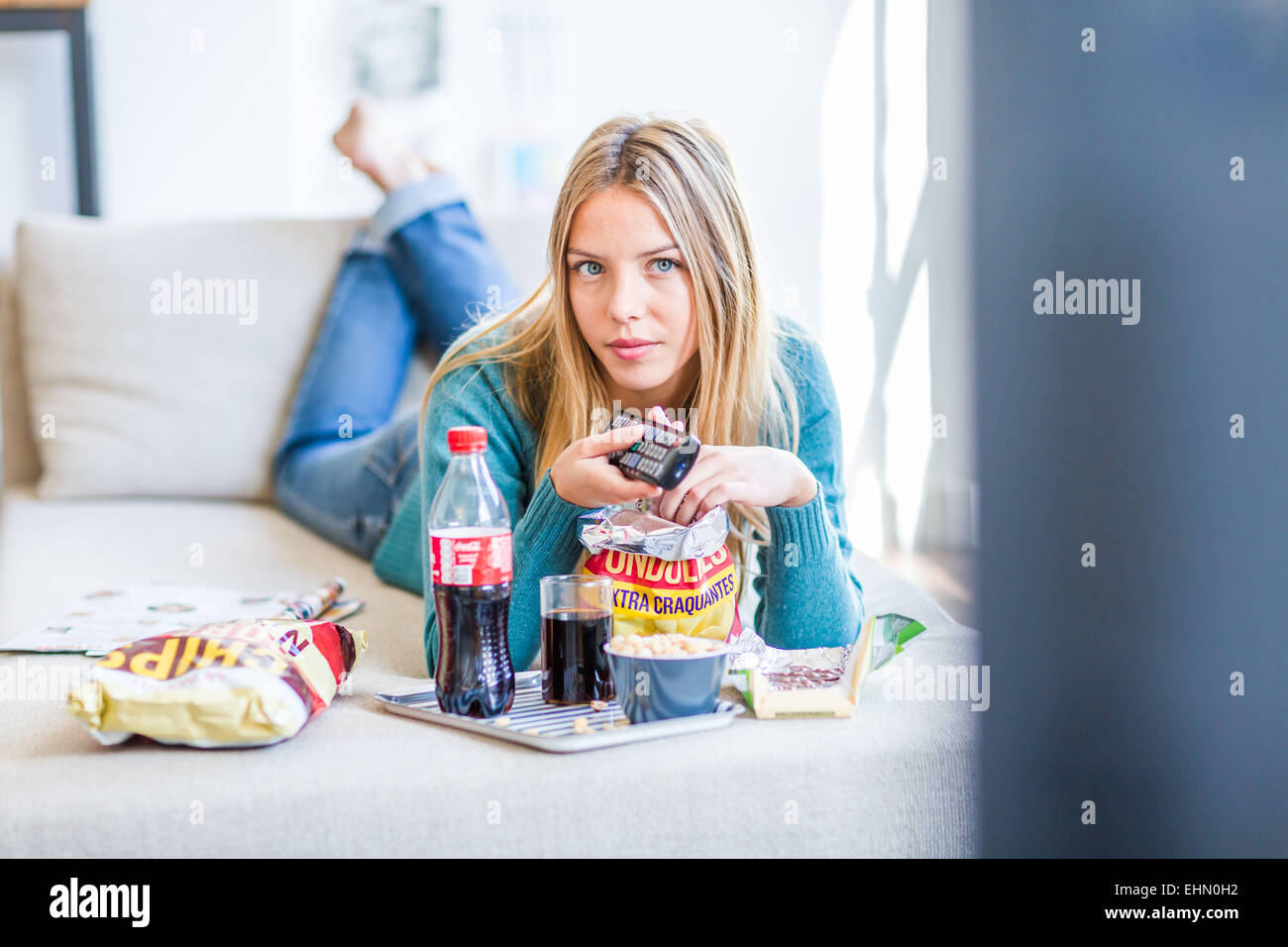 Woman snacking while watching TV. Stock Photo