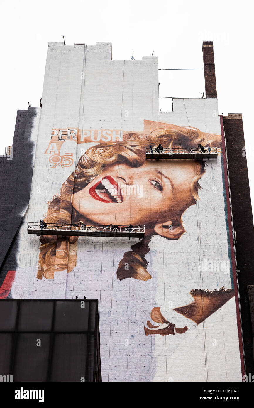 Painters carrying the portrait of a woman on the side of a building, New York City, USA. Stock Photo