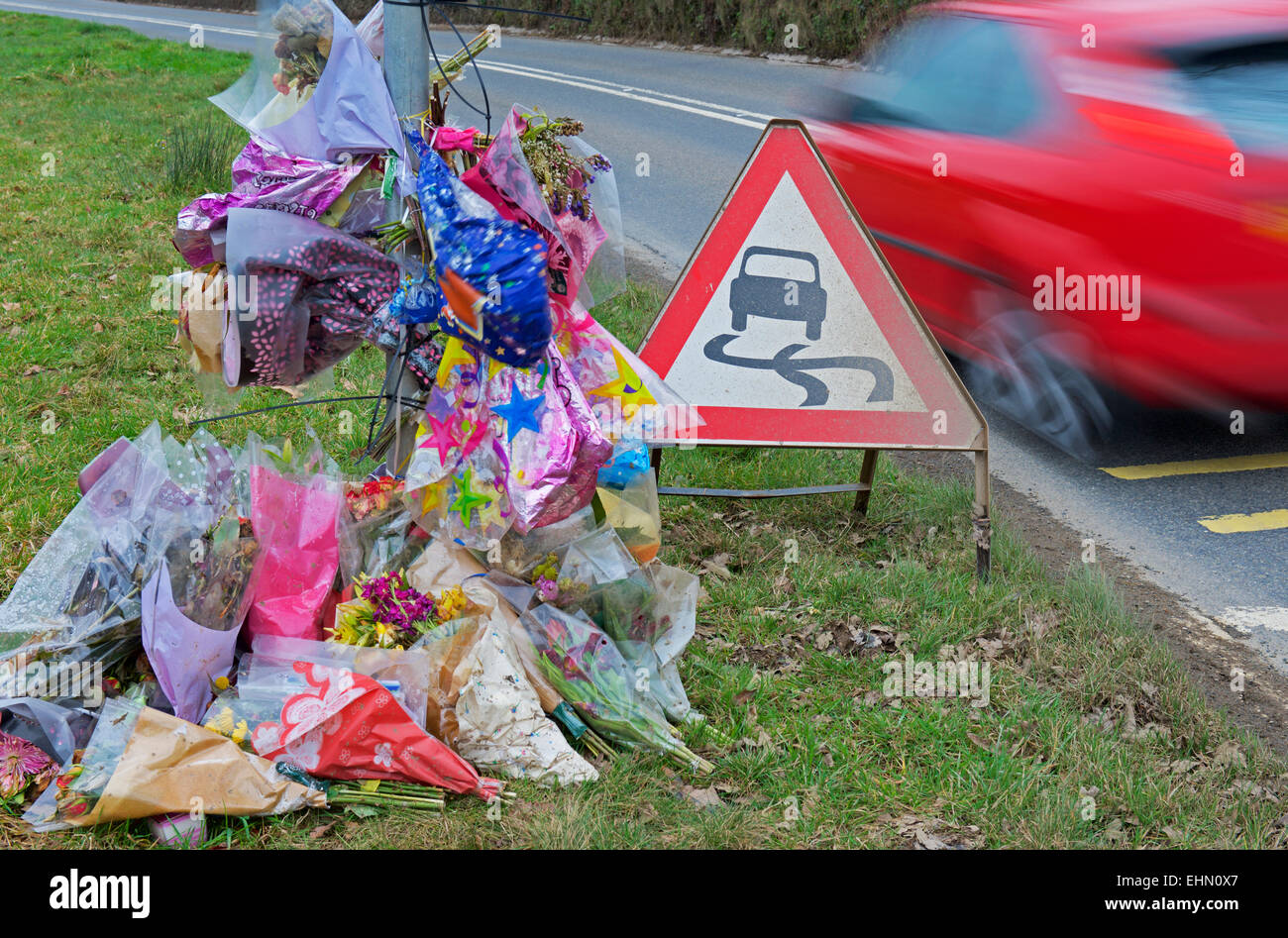 Car speeding past a roadside shrine, the scene of a fatal accident Stock Photo