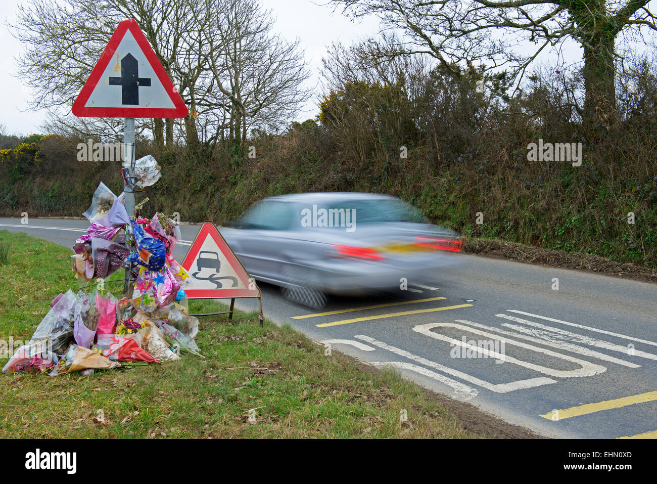 Car speeding past a roadside shrine, the scene of a fatal accident Stock Photo